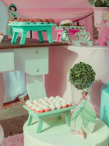 A delightful pink and teal princess-themed party setup with sweets and decorations.